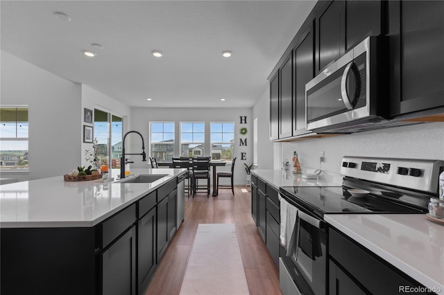 8550 Cheraw St, Littleton, CO 80125 - kitchen featuring stainless steel appliances, dark cabinets, light wood finished floors, light countertops, and recessed lighting