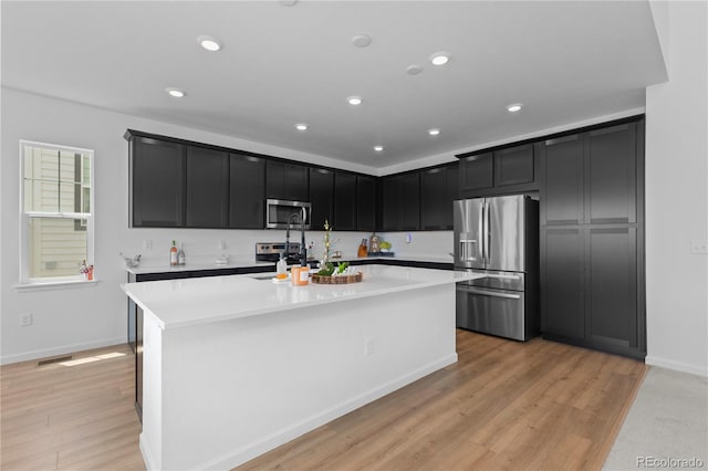 8550 Cheraw St, Littleton, CO 80125 - kitchen with appliances with stainless steel finishes, dark cabinetry, light countertops, light wood-type flooring, and recessed lighting