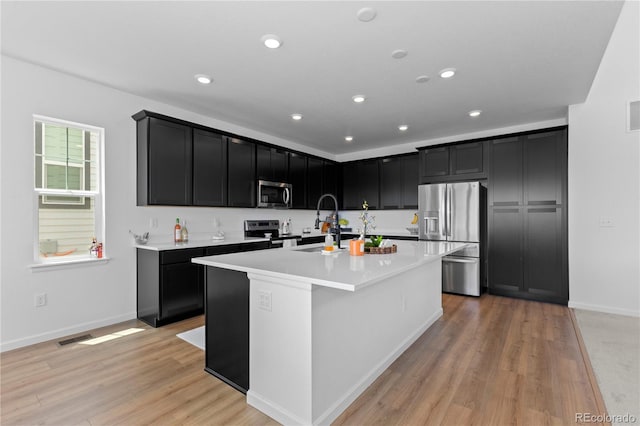 8550 Cheraw St, Littleton, CO 80125 - kitchen featuring appliances with stainless steel finishes, dark cabinets, an island with sink, and recessed lighting