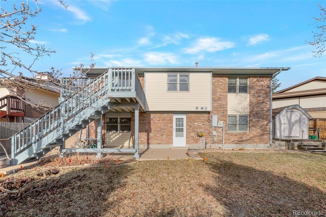 rear view of property featuring a storage unit, stairway, an outdoor structure, brick siding, and a patio area