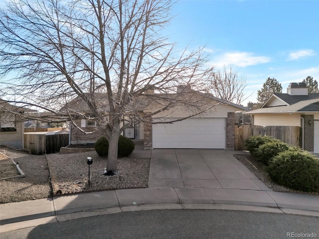 view of front of property featuring a garage, fence, brick siding, and driveway