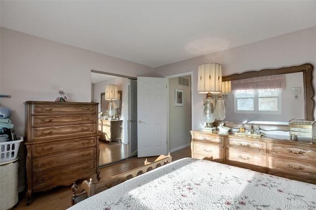 bedroom with wood finished floors, visible vents, and baseboards