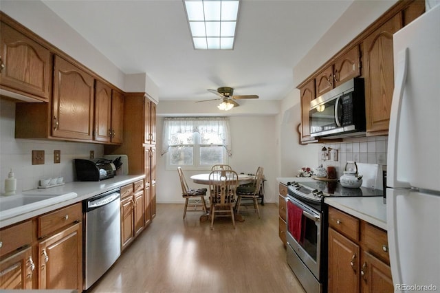 kitchen with light countertops, brown cabinets, appliances with stainless steel finishes, and light wood-type flooring