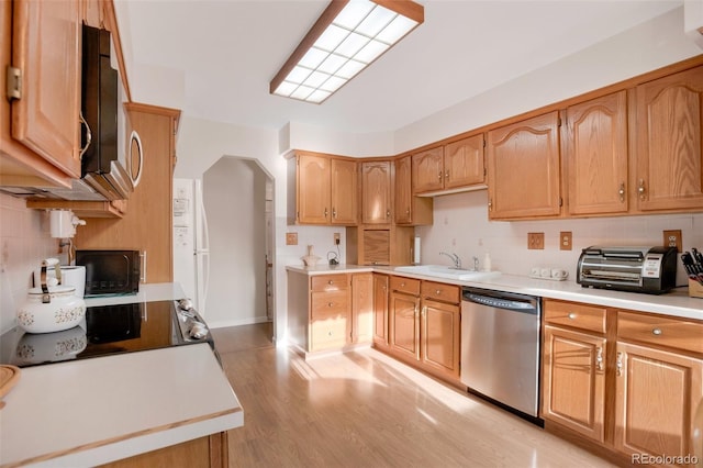 kitchen with tasteful backsplash, light wood finished floors, light countertops, stainless steel appliances, and a sink