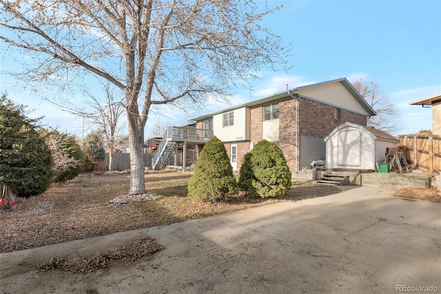 view of front facade featuring brick siding, fence, entry steps, stairs, and a deck