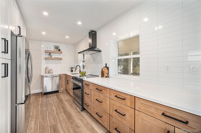 kitchen with sink, backsplash, stainless steel appliances, wall chimney range hood, and light wood-type flooring