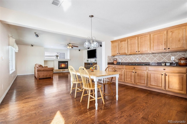 kitchen with dark wood-type flooring, pendant lighting, a breakfast bar area, and tasteful backsplash