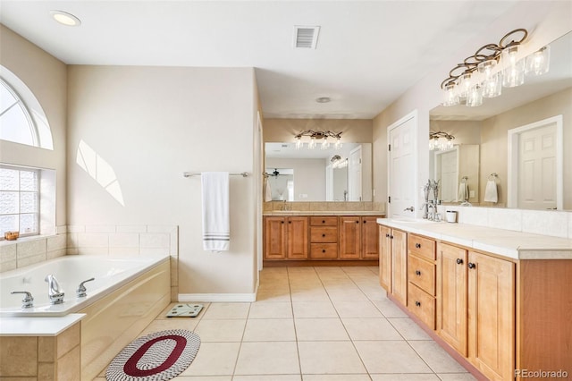 bathroom featuring tile patterned flooring, tiled tub, and vanity