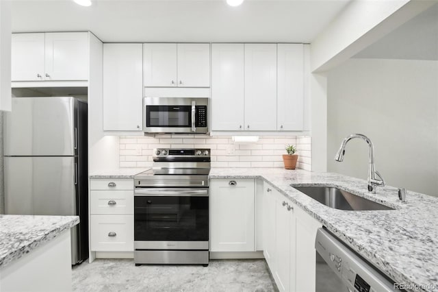 kitchen featuring light stone countertops, sink, decorative backsplash, white cabinets, and appliances with stainless steel finishes