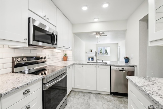 kitchen featuring white cabinets, appliances with stainless steel finishes, light stone counters, and sink