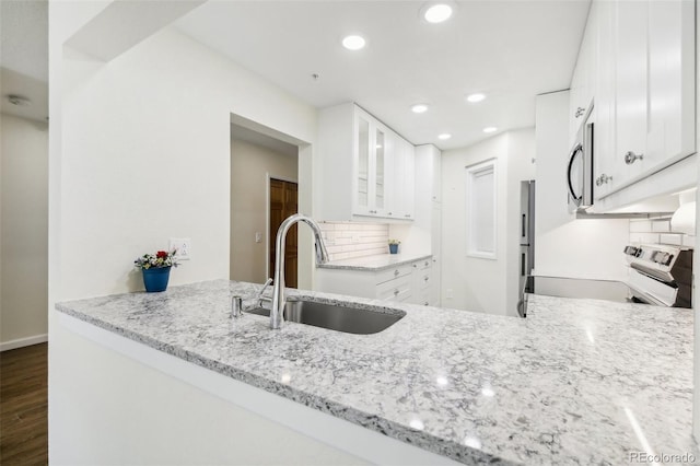 kitchen featuring dark wood-type flooring, white cabinets, sink, electric range, and tasteful backsplash