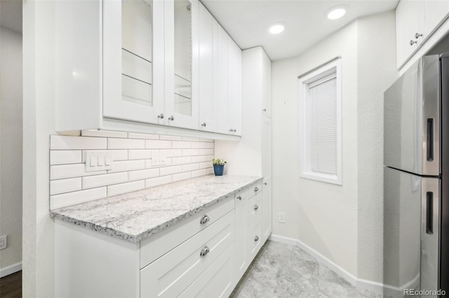 kitchen featuring white cabinetry, light stone countertops, stainless steel fridge with ice dispenser, and tasteful backsplash