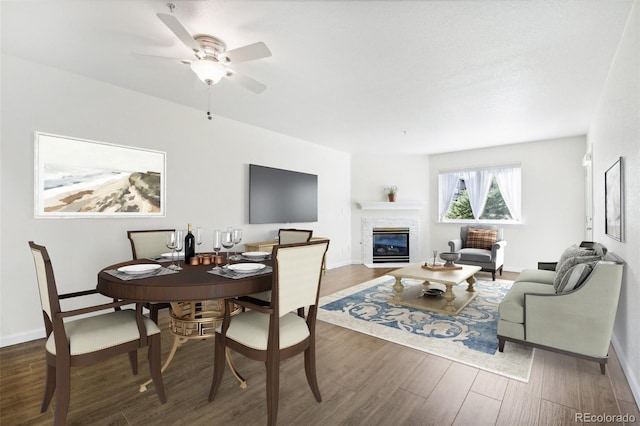 dining room with a fireplace, ceiling fan, and dark hardwood / wood-style flooring