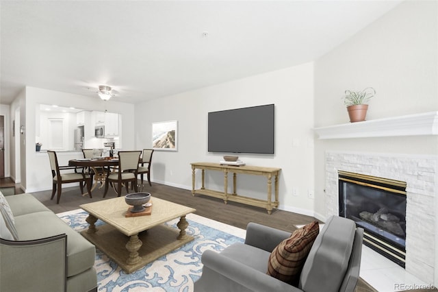 living room featuring a fireplace, ceiling fan, and light hardwood / wood-style flooring