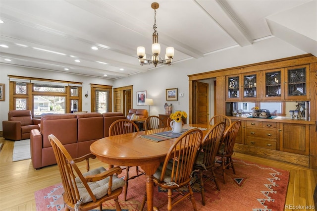 dining space with a notable chandelier, beamed ceiling, and light hardwood / wood-style floors