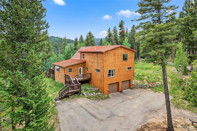 100 Moon Gulch Rd, Rollinsville, CO 80422 - view of front of property featuring a forest view, a deck, asphalt driveway, stairway, and a garage