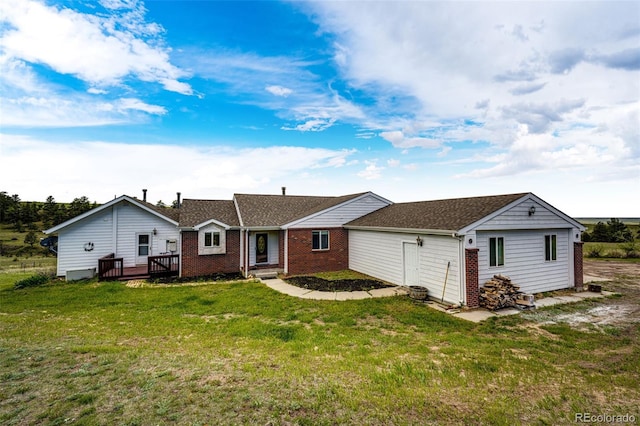 view of front of home featuring a front yard, brick siding, a wooden deck, and a shingled roof