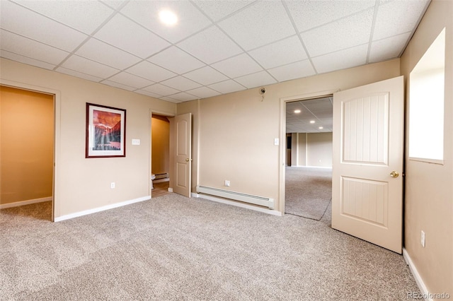 unfurnished bedroom with a baseboard heating unit, carpet flooring, baseboards, a drop ceiling, and a baseboard radiator