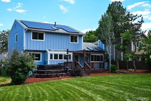 4753 S Gar Way, Littleton, CO 80123 - back of house featuring a hot tub, roof mounted solar panels, a yard, and a deck