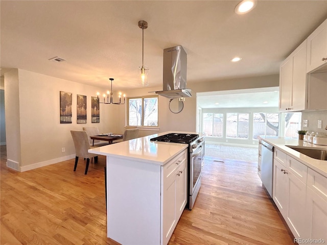 kitchen featuring light wood finished floors, white cabinets, island exhaust hood, stainless steel appliances, and light countertops