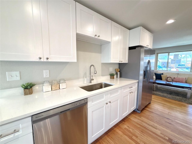 kitchen featuring light countertops, light wood-style flooring, appliances with stainless steel finishes, white cabinets, and a sink