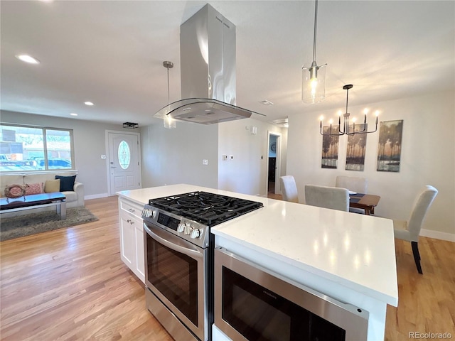 kitchen featuring island exhaust hood, light wood finished floors, stainless steel appliances, open floor plan, and white cabinets