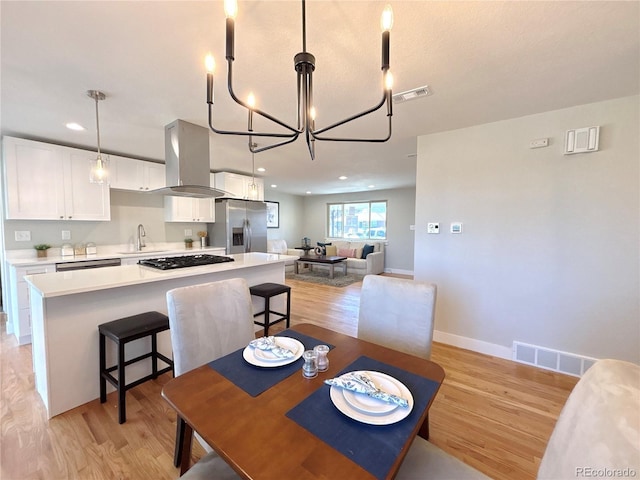 dining room featuring a chandelier, visible vents, light wood-style flooring, and baseboards