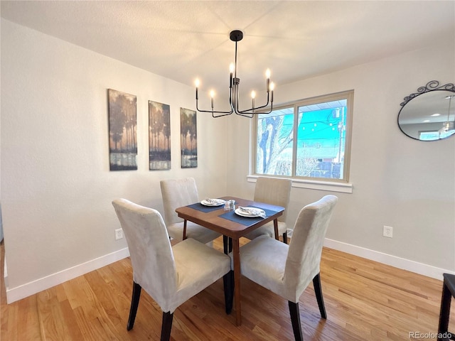 dining area featuring baseboards, a notable chandelier, and light wood finished floors