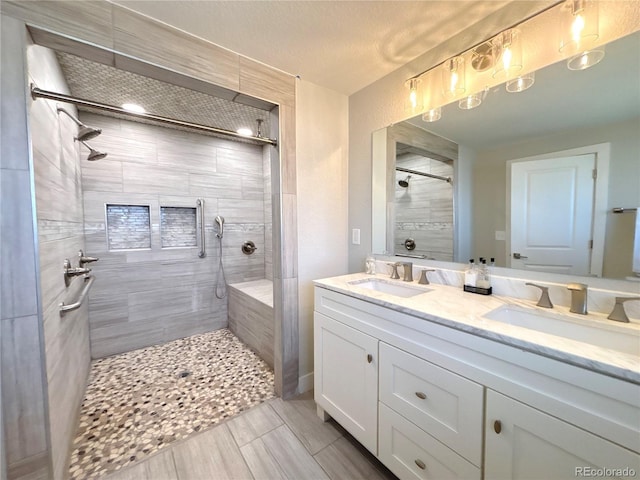 full bath with double vanity, tiled shower, and a sink