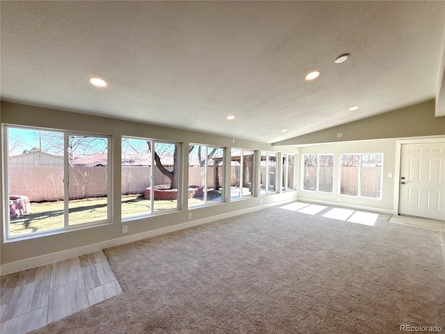 interior space with lofted ceiling, a textured ceiling, recessed lighting, and baseboards