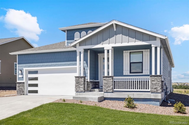 view of front of house featuring a garage, covered porch, and a front yard