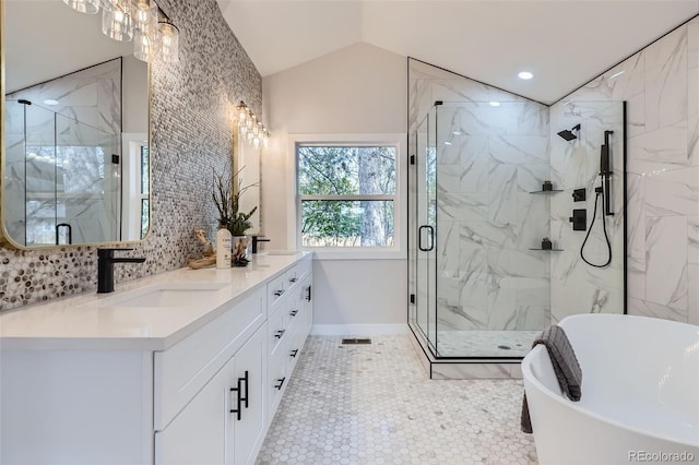 full bathroom featuring a marble finish shower, a sink, double vanity, lofted ceiling, and a freestanding tub