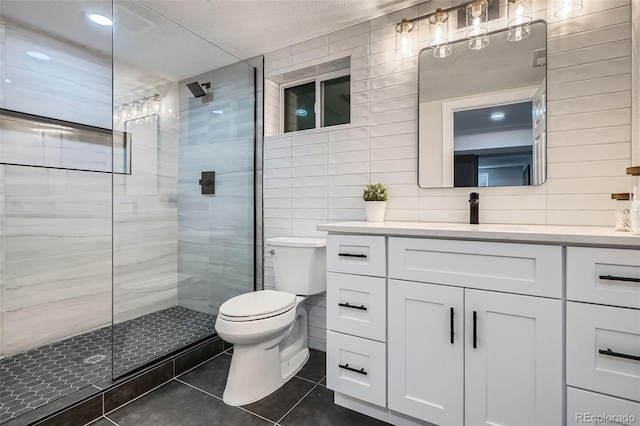 bathroom with toilet, vanity, tile patterned floors, and tiled shower