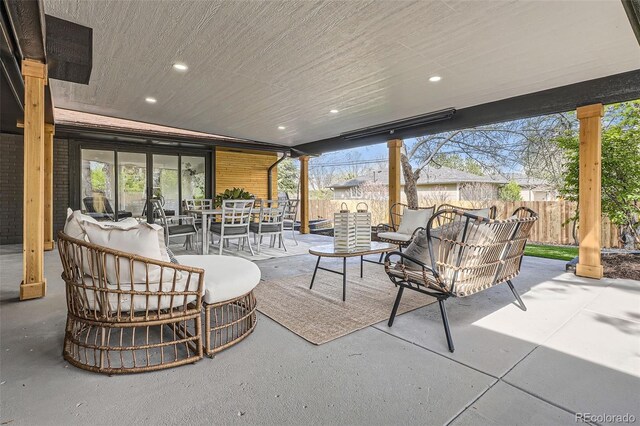 view of patio featuring outdoor dining area, fence, and an outdoor living space