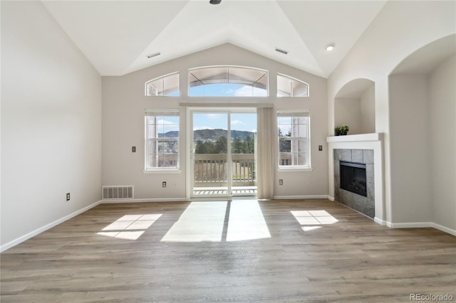 unfurnished living room featuring a tile fireplace, lofted ceiling, wood finished floors, and baseboards
