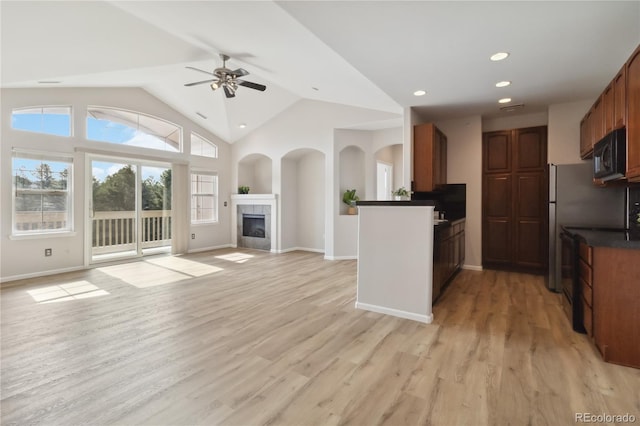 kitchen featuring a ceiling fan, dark countertops, a fireplace, light wood-style floors, and black microwave