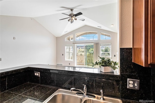 kitchen featuring lofted ceiling, ceiling fan, visible vents, a sink, and dark countertops