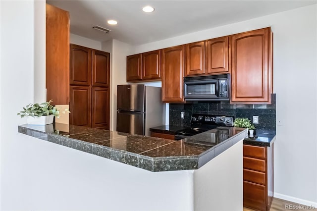kitchen featuring tile counters, visible vents, a peninsula, decorative backsplash, and black appliances