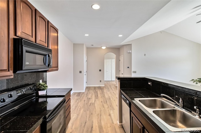 kitchen with black appliances, a sink, light wood-type flooring, decorative backsplash, and recessed lighting