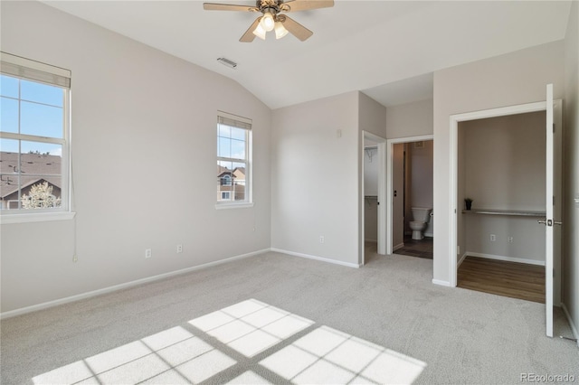 unfurnished bedroom with carpet flooring, baseboards, lofted ceiling, and ensuite bathroom