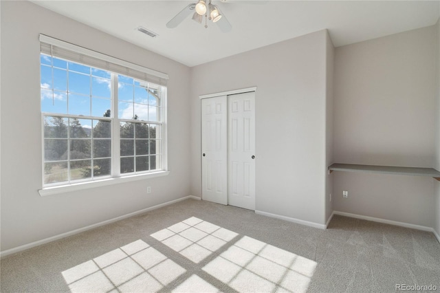 unfurnished bedroom with carpet floors, baseboards, a closet, and ceiling fan