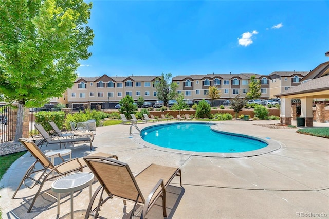 community pool with a residential view, a patio area, and fence