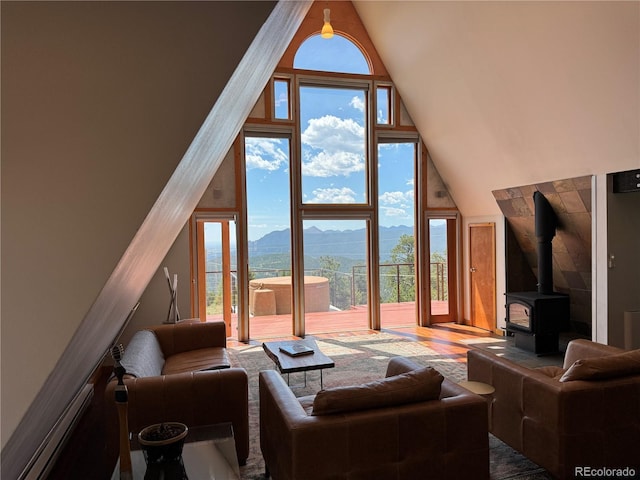 living room with hardwood / wood-style floors, a high ceiling, expansive windows, a mountain view, and a wood stove