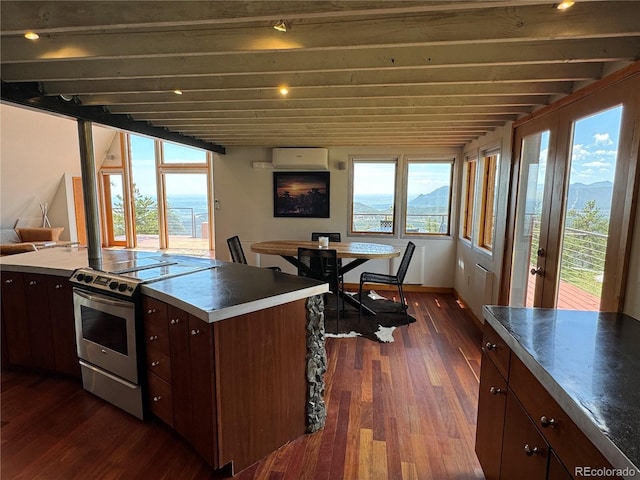 kitchen featuring dark wood-type flooring, stainless steel electric range oven, a mountain view, and a wall mounted air conditioner