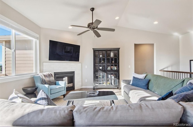 living area featuring wood finished floors, ceiling fan, baseboards, a fireplace, and lofted ceiling