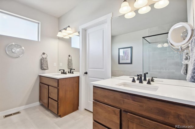 bathroom with two vanities, a shower stall, visible vents, and a sink