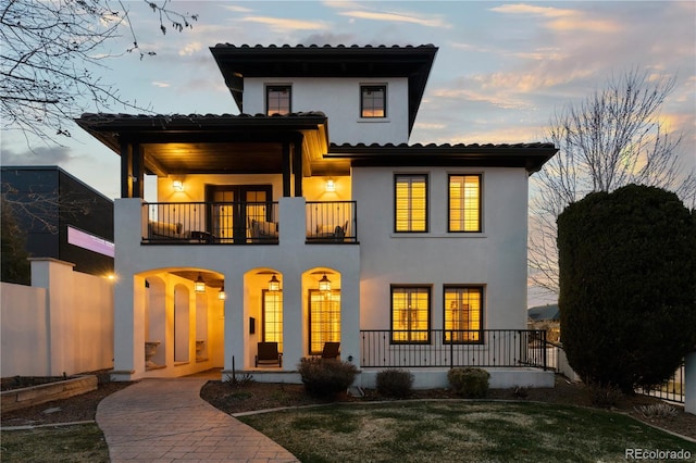 mediterranean / spanish home with covered porch, a balcony, and stucco siding