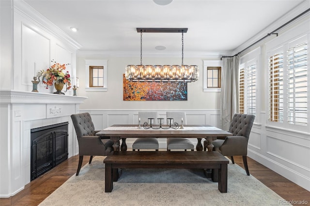 dining space with ornamental molding, a glass covered fireplace, a healthy amount of sunlight, and a decorative wall