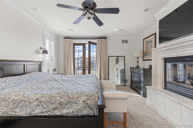 bedroom with carpet floors, visible vents, crown molding, and a glass covered fireplace