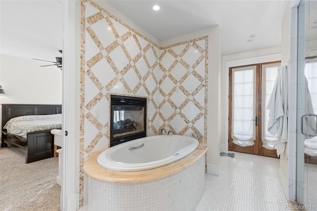 ensuite bathroom with french doors, a tiled fireplace, ensuite bath, tile patterned flooring, and a bath